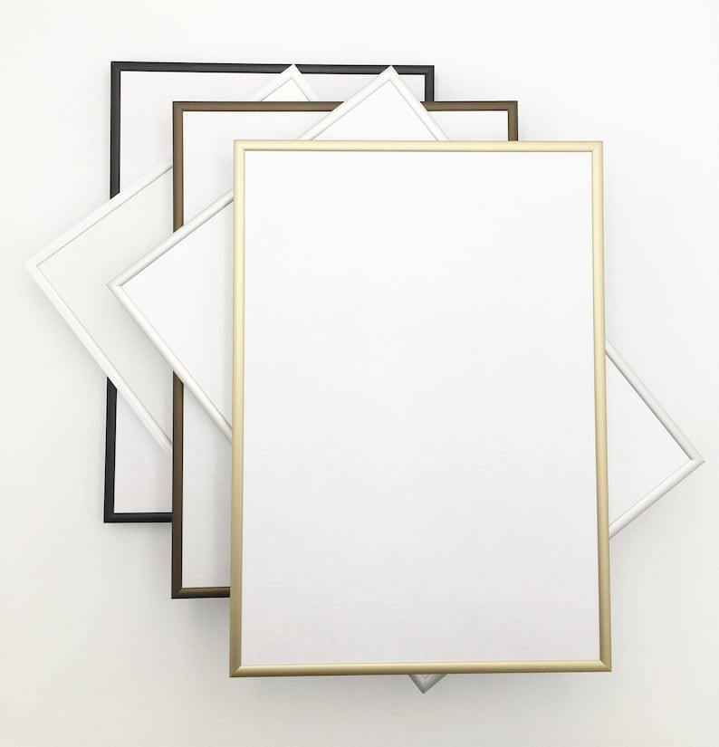 May include: Four picture frames in different colors, black, brown, gold, and white. The frames are stacked on top of each other, with the gold frame in the front.