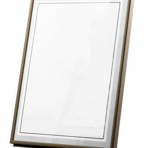 May include: A gold-toned picture frame with a white mat and a black inner border. The frame is angled slightly to the right.