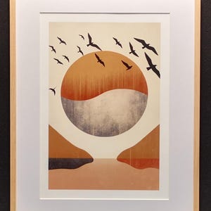 Op de afbeelding: Een ingelijste print van een minimalistisch abstract landschap met een grote oranje en grijze cirkel in het midden, omringd door een zwerm zwarte vogels die in de lucht vliegen. De achtergrond is in gedempte oranje en bruine tinten.