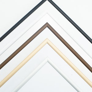 Peut inclure: Vue a&eacute;rienne de quatre cadres photo dispos&eacute;s en diagonale. Les cadres sont noirs, blancs, marron et beige. Les cadres sont inclin&eacute;s, r&eacute;v&eacute;lant leurs coins et bords int&eacute;rieurs sur fond blanc. Les cadres sont probablement destin&eacute;s &agrave; afficher des &oelig;uvres d'art ou des photographies.