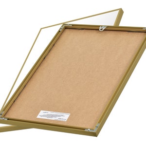 May include: A gold picture frame with a brown backing. The frame is open and the backing is visible. The frame is made of metal and has a simple design.