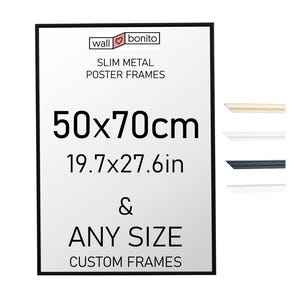 Puede incluir: Un marco de póster rectangular de metal negro fino con espacio interior blanco. El texto dice: wall bonito, SLIM METAL POSTER FRAMES, 50x70cm, 19.7x27.6in, & ANY SIZE CUSTOM FRAMES. Se muestran cuatro muestras de perfiles de marco en beige, blanco, negro y blanco.