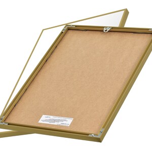 May include: A gold picture frame with a brown backing. The frame is open and the backing is visible. The frame is made of metal and has a simple design.