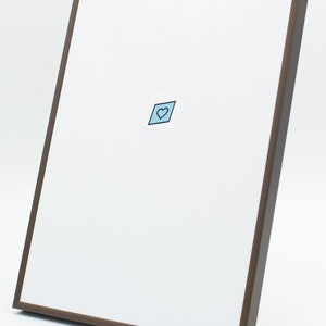 Peut inclure: Un tableau blanc encadr&eacute; de marron, avec un petit autocollant en forme de c&oelig;ur bleu. Le cadre est marron fonc&eacute; et le tableau est inclin&eacute;, sur fond blanc.