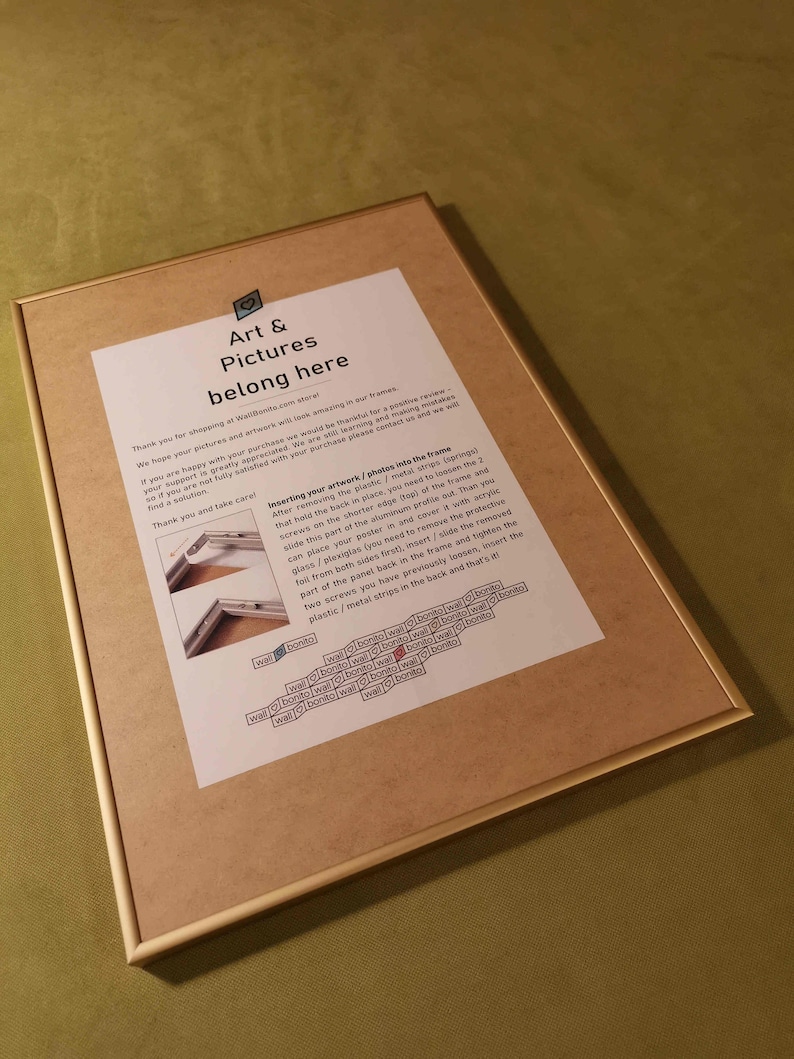 May include: A framed instruction sheet with a gold frame and a white background. The text explains how to insert artwork or photos into the frame. The text includes the words "Art & Pictures belong here".