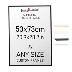 Może przedstawiać: Prostokątna, cienka metalowa rama do plakatu w kolorze czarnym z napisem wall bonito SLIM METAL POSTER FRAMES 53x73cm 20.9x28.7in & ANY SIZE CUSTOM FRAMES. Po prawej stronie znajdują się cztery próbki cienkich profili ram w kolorach beżowym, białym, czarnym i srebrnym.