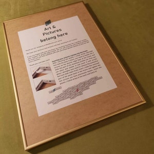 以下が含まれることがあります： アートと写真を入れる方法が書かれた、茶色の木製の額縁のクローズアップ。テキストには「Art & Pictures belong here」と「Inserting your artwork/photos into the frame」と書かれています。