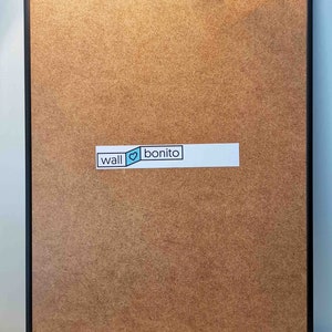 May include: A black framed corkboard with a white sticker that says "wall &hearts; bonito".