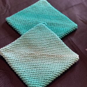May include: Two crocheted teal pot holders with a gradient of color from light to dark teal.