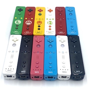 May include: A collection of colorful Wii remotes. The remotes are in various colors, including green, red, yellow, white, and blue. Each remote has a plus-shaped directional pad, buttons, and the "Wii" logo.