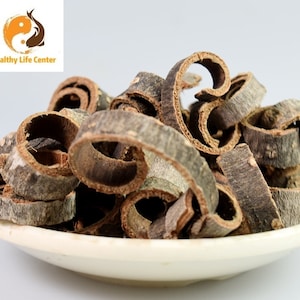 May include: A white ceramic dish filled with dried, curled cinnamon bark pieces.