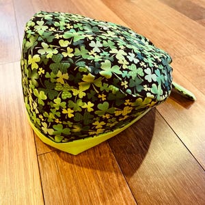 Peut inclure: Un bonnet de travail vert et noir avec un imprimé trèfle et une bordure vert citron.