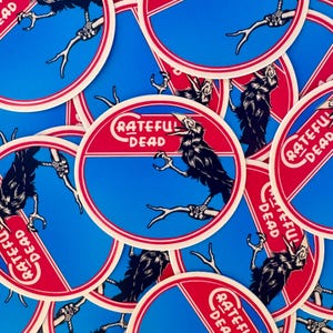 May include: Circular stickers with a blue background, red and white border, and a red horizontal stripe. The stickers feature a black crow perched on a branch, with the words "Grateful Dead" in a white, stylized font.
