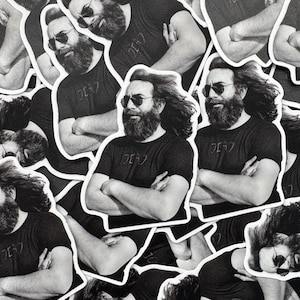 May include: Black and white stickers featuring a man with a long beard, sunglasses, and a t-shirt with text. The stickers are die-cut with a white border. The man has his arms crossed and is looking forward.