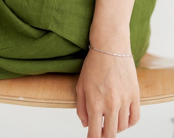May include: A silver chain bracelet with small rectangular links.