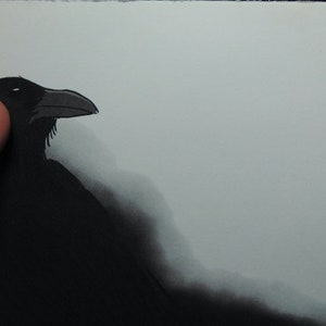 May include: A black crow with a dark gray background. The crow is facing to the right and has its head tilted slightly to the side.