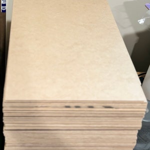 May include: A stack of plain, light brown, rectangular pieces of wood.