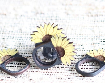 May include: Four wooden napkin rings with sunflower designs. The rings are painted yellow and brown and have a natural wood finish.