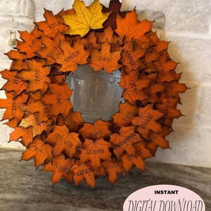 May include: A laser-cut wreath made of orange wooden maple leaves, each with a name engraved. The wreath has a clear glass cylinder in the center. Text on the image reads "LASER CUT READY" and "SVG CUT FILE".