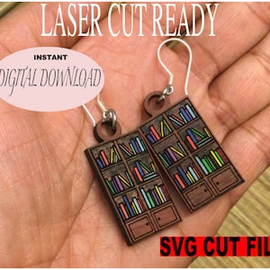 May include: A pair of wooden earrings shaped like bookshelves filled with colorful books. The earrings are laser cut ready and come with an instant digital download of the SVG cut file.
