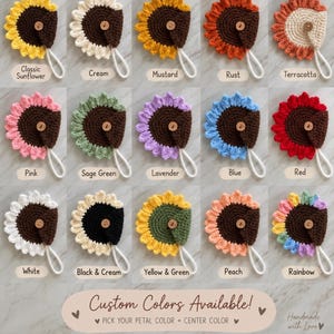 May include: A collection of fifteen crocheted sunflower-shaped cord organizers, each featuring a central wooden button and a small loop. The items are displayed in various colors including yellow, cream, mustard, rust, terracotta, pink, sage green, lavender, blue, red, white, black, and rainbow.