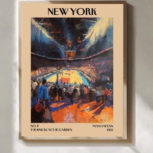 May include: A framed art print depicting a basketball game at Madison Square Garden, titled "New York." The painting shows the arena's interior, with a crowd and players on the court. Text includes "No. 8 The Knicks at the Garden Manhattan 1955." The artwork is in a beige frame.
