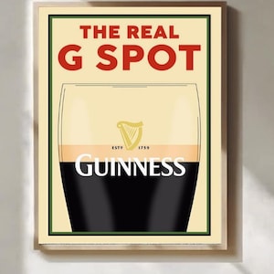 May include: Framed print of a Guinness pint, with the text "THE REAL G SPOT" in red. The Guinness logo and name are visible. The background is a light beige color, and the print is in a wooden frame.