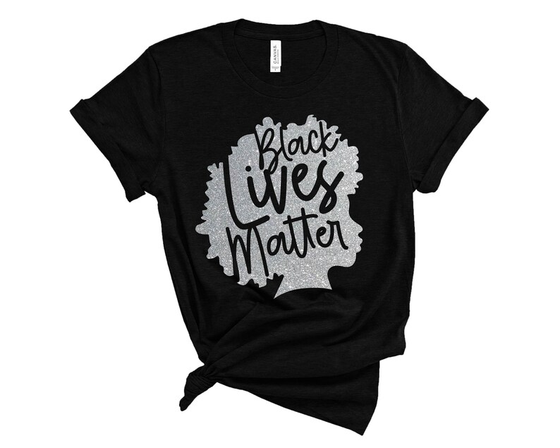 May include: Black t-shirt featuring a silver glitter design of a silhouette with the words "Black Lives Matter". The shirt is knotted at the bottom. The design is a statement of solidarity and support.