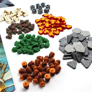 May include: A selection of board game pieces in different shapes and colours. Includes wooden-style pieces, green and brown tree-like pieces, red flame-shaped pieces, grey shield-shaped pieces, and brown acorn-shaped pieces, all on a white surface.