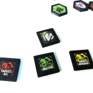 Puede incluir: Cinco fichas cuadradas negras de juego con diferentes imágenes y textos. Las fichas están sobre una superficie blanca. El texto en las fichas dice "Torreta", "Inactivo", "Objetivo: Todo", "Objetivo: Intruso" y "Objetivo: Todo".