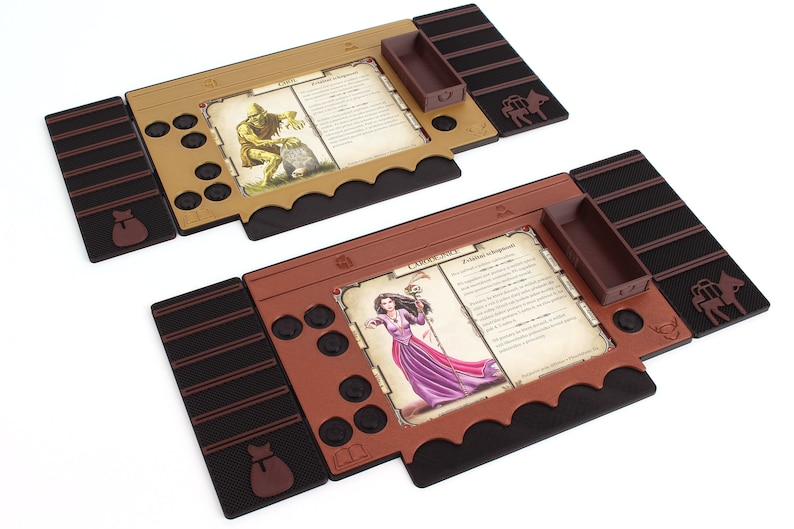 Pu&ograve; includere: Due tavoli da gioco marroni e neri con un vassoio marrone, una borsa marrone e una figura di animale marrone. I tavoli hanno uno slot per carte e uno spazio per una carta. Gli slot per carte hanno una carta con un'immagine di un mostro e una strega. Il testo sulle carte recita "Goblin" e "Clobberella".