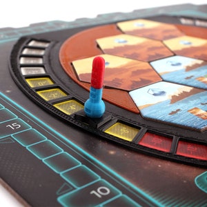 May include: A close-up of a game board with a red and blue temperature slider. The slider is set to -4 degrees. The board is made of black plastic and has a futuristic design.