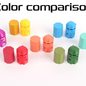 Op de afbeelding: Kleurvergelijking van tien 3D-geprinte miniatuurtorens. De torens zijn in de volgende kleuren: paars, roze, rood, oranje, geel, blauw, groen, turquoise en lichtgroen.