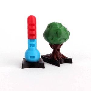 May include: A red and blue thermometer and a green tree on black bases. Both are 3D printed.