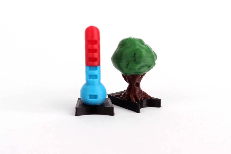 May include: A red and blue thermometer and a green tree on black bases. Both are 3D printed.