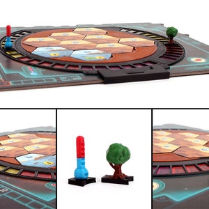 May include: A board game with a circular playing area featuring hexagonal tiles in shades of brown, orange, and blue. The game includes red and blue game pieces, and green tree pieces. The board is made of cardboard and has a black plastic frame.