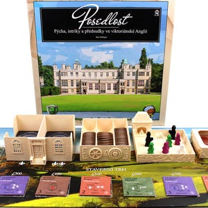 May include: Board game titled "Posedlost" with components including miniature buildings, tokens, and player pieces. The game board features a landscape scene and cards. The box art displays a large building with a green lawn.