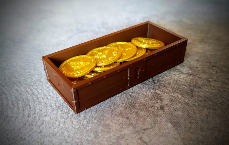 Pu&ograve; includere: Un forziere di legno marrone pieno di monete d'oro. Le monete hanno un disegno di un'ape.