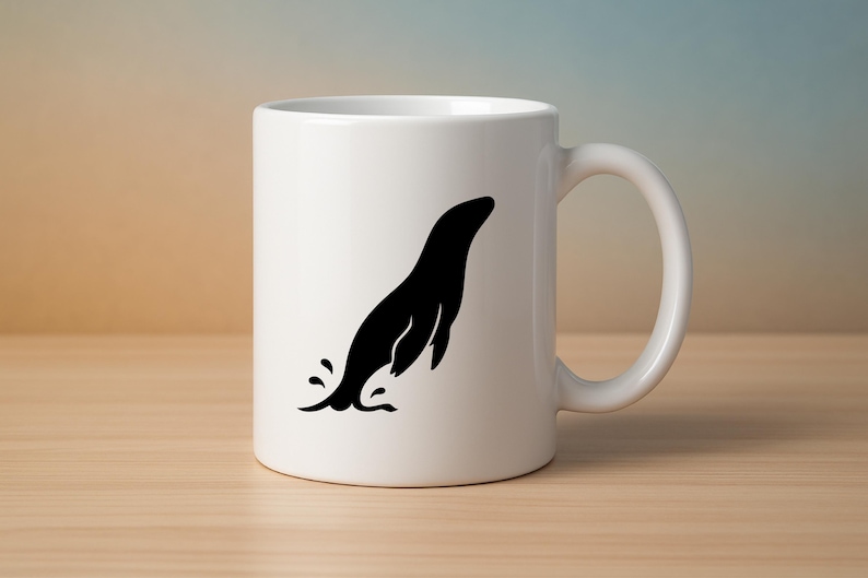 May include: White ceramic mug featuring a black silhouette of a seal leaping out of water. The mug has a curved handle and is set on a light brown wooden surface. The background has a gradient of beige, blue, and white.