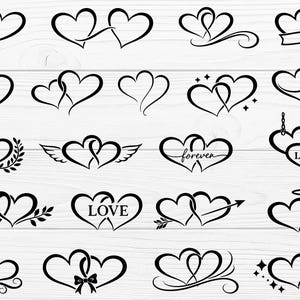May include: A collection of black heart designs on a white wooden background. The hearts are intertwined, with variations including wings, arrows, laurel wreaths, and the word "LOVE". Some designs have a ribbon or a halo.