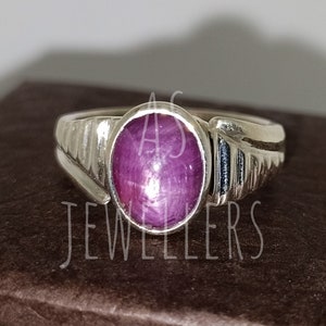 May include: A silver ring with a pink oval-shaped gemstone. The ring has a textured band.