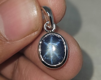 May include: A silver pendant featuring a blue star sapphire gemstone with a six-pointed star.