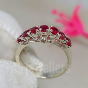 Puede incluir: Un anillo de plata con una fila de piedras preciosas rojas engastadas en un delicado engaste de garras.