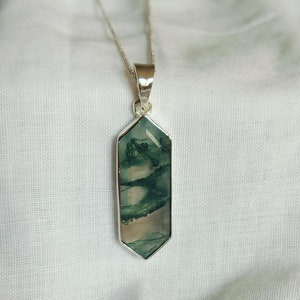 Op de afbeelding: Een zilveren ketting met een groene agaat hanger in een gefacetteerde, geometrische vorm.