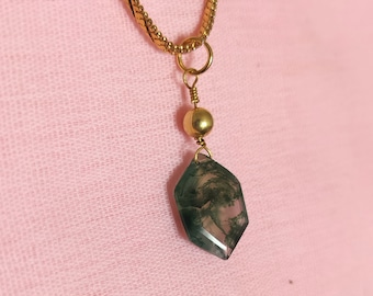 May include: A gold chain necklace with a green and white agate pendant. The pendant is a faceted, geometric shape.