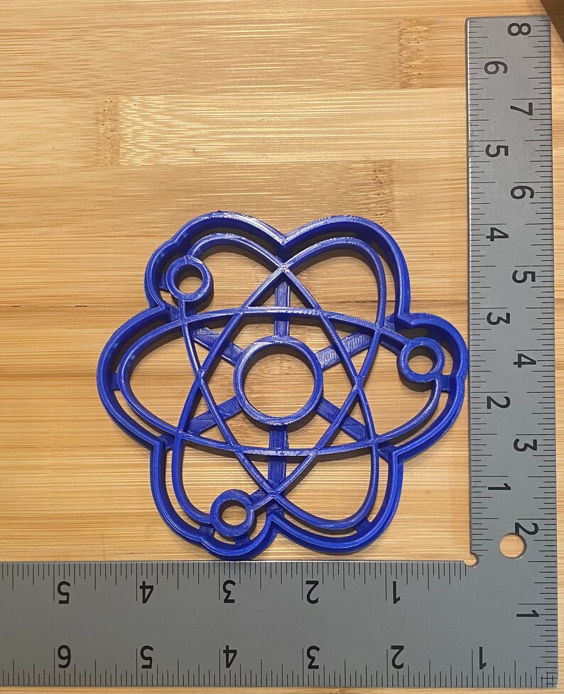 May include: A blue plastic cookie cutter shaped like an atom. The cutter is about 2 inches in diameter.
