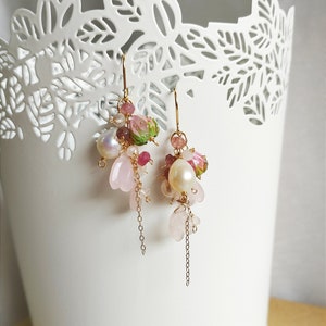 May include: Pink and green floral earrings with gold chain accents and pearl beads.