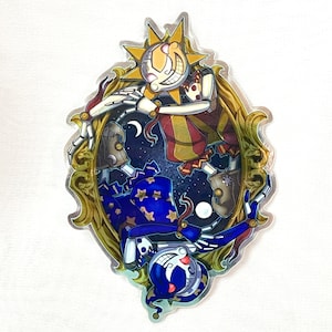 May include: A silver foil sticker featuring two skeletal figures, one with a sun and the other with a moon on their heads, against a starry night background. The figures are in a playful pose, with the sun figure holding a crescent moon and the moon figure holding a star.