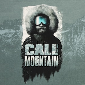 Könnte beinhalten: Ein schwarz-weißes Grafikdesign mit einem Mann, der eine Wintermütze und eine Skibrille trägt. Der Text "CALL OF THE MOUNTAIN" ist in einer verwitterten Schriftart.