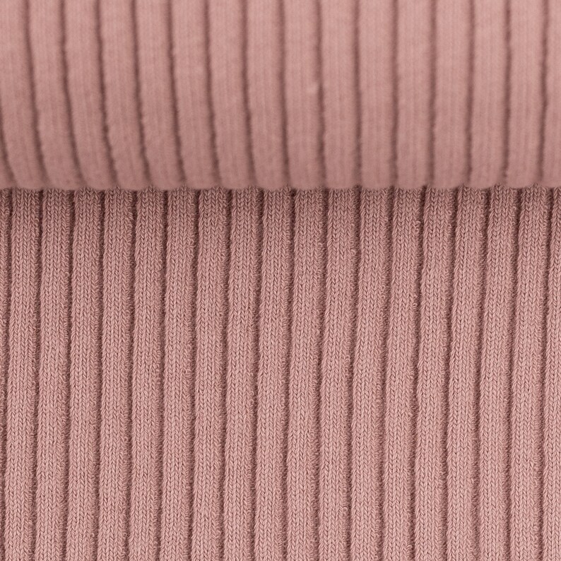May include: Close-up of a ribbed fabric in a dusty rose color. The fabric is soft and has a subtle texture.